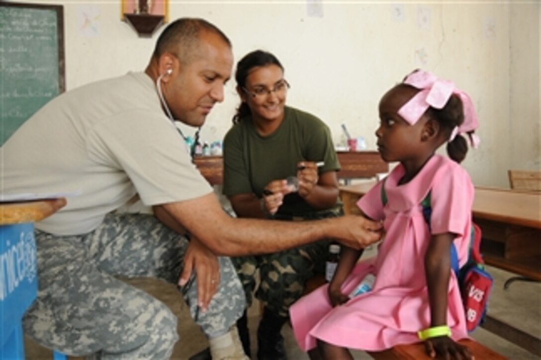 U.S. Army Maj. Jose Rivera, a doctor with the 94th Combat Support Hospital (left) works alongside a Uruguayan Navy nurse to examine a young Haitian schoolgirl during a U.S. Army Medical Readiness Training Exercise in Couteaux, Haiti, on April 30, 2010.  The unit is working alongside Haitian medical care providers to offer free level-one medical care to Haitians in the community during Operation Unified Response.  