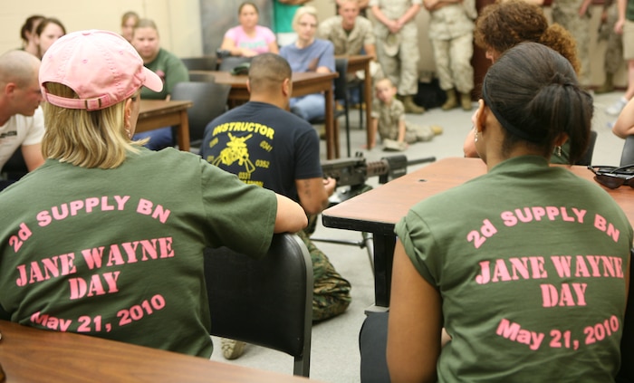 The wives and other family members of Marines with 2nd Supply Battalion, Combat Logistics Regiment 25, 2nd Marine Logistics Group, listen and watch as an indoor simulated marksmanship trainer (ISMT) instructor briefs them on various characteristics of weapons they will be firing in the ISMT during Jane Wayne Day aboard Camp Lejeune, N.C., May 21, 2010. Family members fired a variety of simulated weapons before heading to the range for the real thing.  (U.S. Marine Corps Photo by Lance Cpl. Katherine M. Solano)