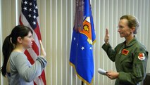 Coming over from Active Duty to the Reserves,Senior Airman Maria Schoenecker, 940th Wing Services Flight's newest member, re-enlists in the commander's office, May 21, at Beale Air Force Base, Calif.  Col Devine, 940th Wing Vice Commander, administers the oath. (U.S. Air Force/Airman 1st Class Adam Hamar)
