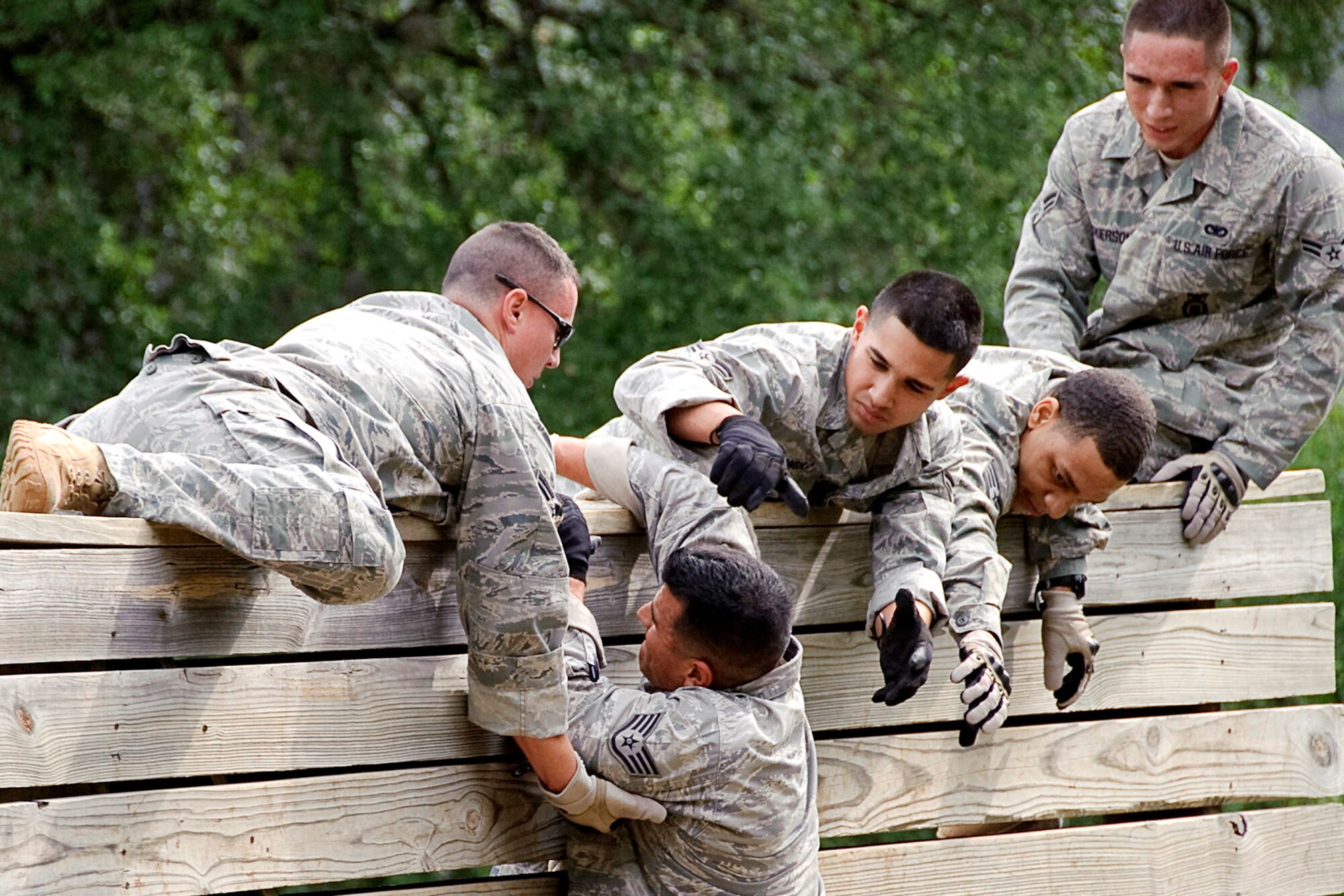 Airmen from the 902nd Security Force Squadron at a Randolph Air Force Base, Texas, work together to climb over a high wall at Camp Bullis, Texas, while participating in an obstacle course May 12, 2010, during a National Police Week event. (U.S. Air Force photo/Steve Thurow)
