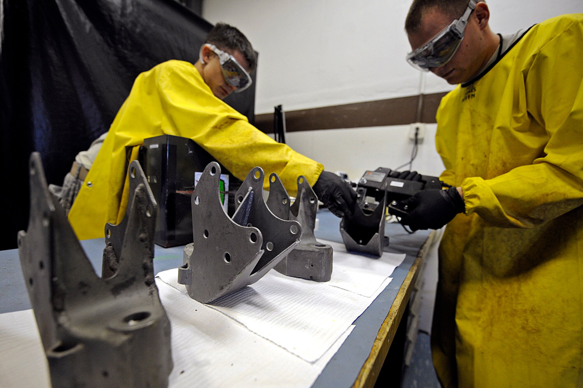 ELLSWORTH AIR FORCE BASE, S.D. – (Left) Airman 1st Class Evan Bryant and Staff Sgt. Ehud Torres, 28th Maintenance Squadron non-destructive inspection technicians, use a magnetic yoke to magnetize the forward support brackets prior to inspection, May 20. The magnetic yoke works in conjunction with the portable magnetic particles pulling them into cracks and making them visible under an ultraviolet light. (U.S. Air Force photo/Airman 1st Class Matthew Flynn)