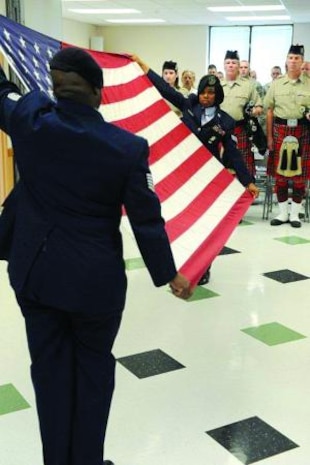Tech. Sgt. Sean Hannah, 75th Air Base Wing, and Senior Airman Aletha Sanford, 75th Security Forces Squadron, prepare to fold the flag before its presentation to Maj. John J. Dumont III, 75th Security Forces Squadron commander. (U.S. Air Force photo by Alex Lloyd)