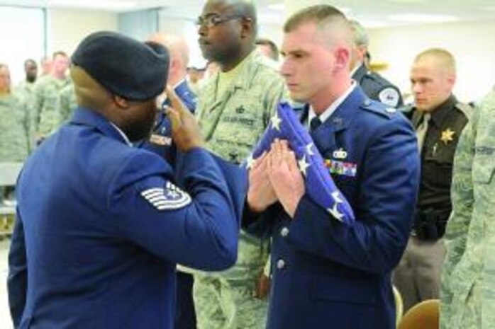 Tech. Sgt. Sean Hannah, 75th Air Base Wing, presents a folded flag to Maj. John J. Dumont II, 75th Security Forces commander, at the Retreat Ceremony held May 14 for National Police Week and in remembrance of all security forces and Office of Special Investigations personnel who have lost their lives in the performance of their military duty. Members of other police departments took part in the observance, which also honored nonmilitary police service deaths. (U.S. Air Force photo by Alex Lloyd)
