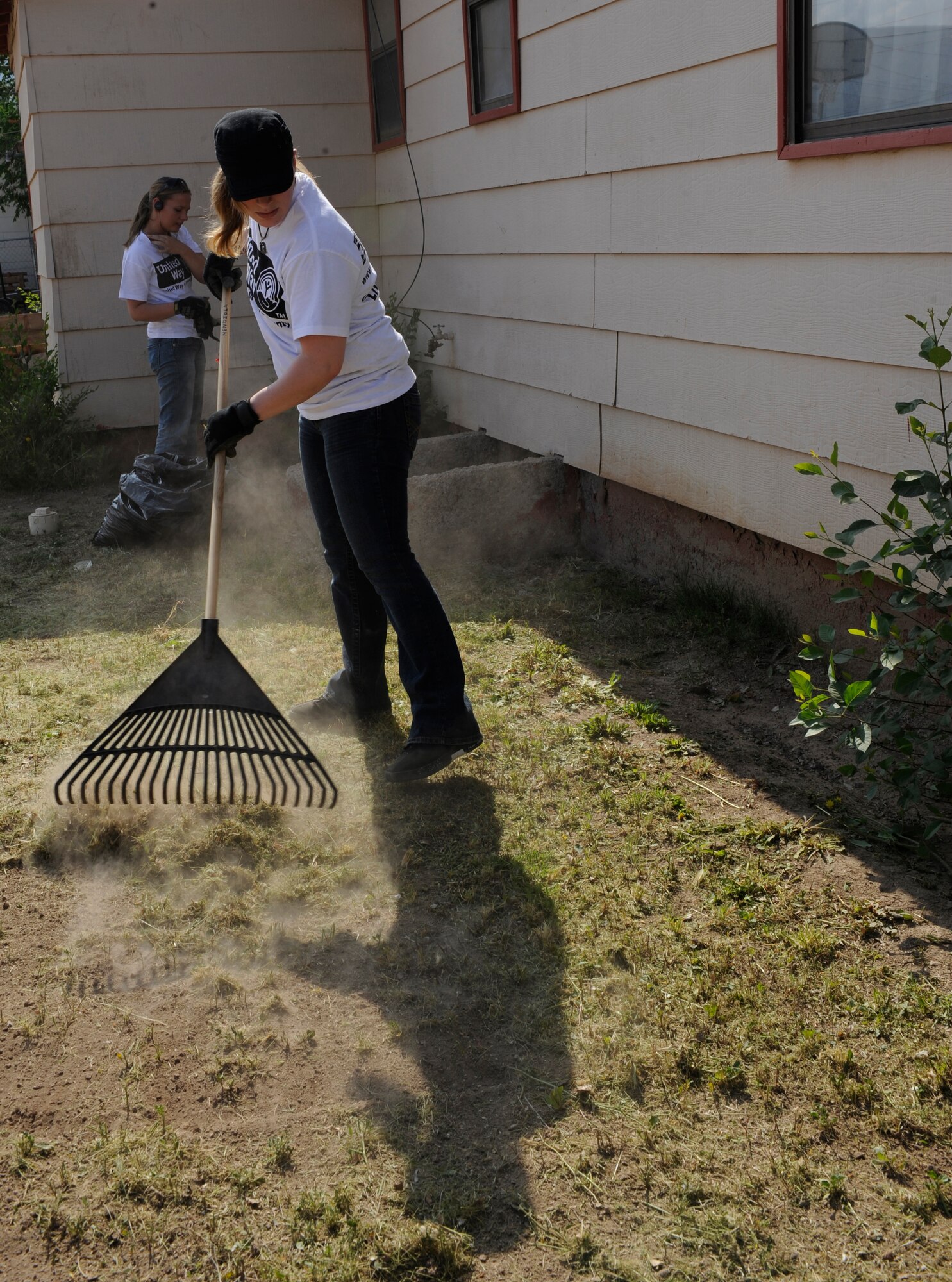 ALAMOGORDO, N.M. -- Senior Airman Kristen Miller, from the 49th Communications Squadron at Holloman Air Force Base, rakes grass after mowing the lawn at an Alamogordo home during the United Way Day of Caring May 14, 2010. Members of Team Holloman performed a variety of jobs during the annual volunteering event, from mowing lawns, trimming trees, pulling weeds and painting homes, in an effort to help out the local community.  (U.S. Air Force photo by Airman 1st Class Eileen Payne / Released)