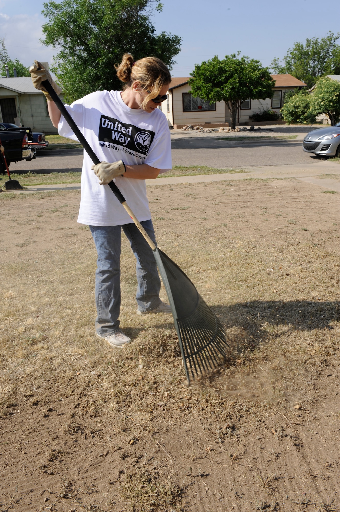 ALAMOGORDO, N.M. -- Tech. Sgt. Denise Mendiola, from the 49th Communications Squadron at Holloman Air Force Base, rakes grass after mowing the lawn at Alamogordo home during the United Way Day of Caring May 14, 2010. During the annual event, volunteers from Team Holloman went out into the local community to do yard and house work for those who are unable because of physical and financial disabilities. (U.S. Air Force photo by Airman 1st Class Eileen Payne / Released)