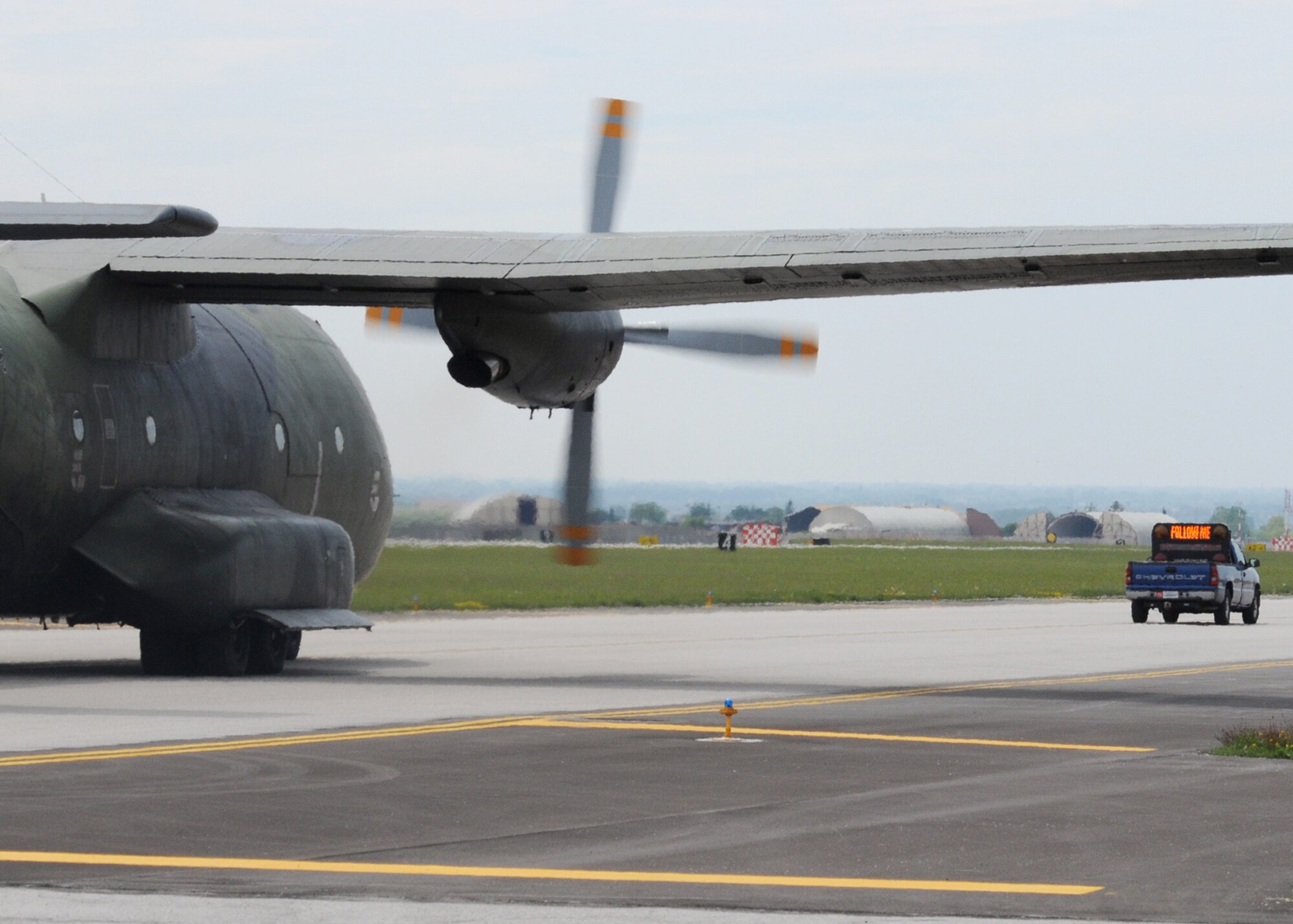 A blue "Follow Me" truck leads the way for aircraft visiting Aviano's flightline. The Transit Alert provides services to aircraft not assigned to Aviano. These aircraft include NATO forces, rotators taking Airmen to and from various locations, C-130 Hercules used to support joint exercises, and those belonging to friendly foreign nations. (U.S. Air Force photo/ Senior Airman Tabitha Mans)