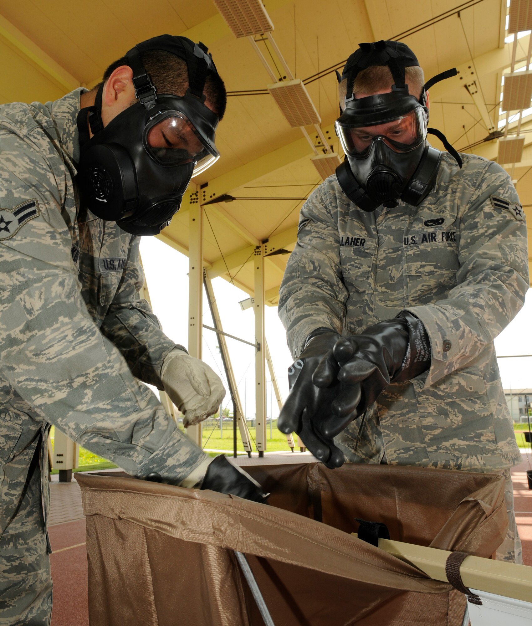 SPANGDAHLEM AIR BASE, Germany – Airman 1st Class Raymond Kim, left, 52nd Component Maintenance Squadron, and Airman 1st Class Chris Gallaher, 52nd Equipment Maintenance Squadron, remove their gloves at the last station of a contamination control area May 20. Both Airmen volunteered to process through the CCA in preparation for the upcoming NATO Force Evaluation. (U.S. Air Force photo/Senior Airman Benjamin Wilson)
