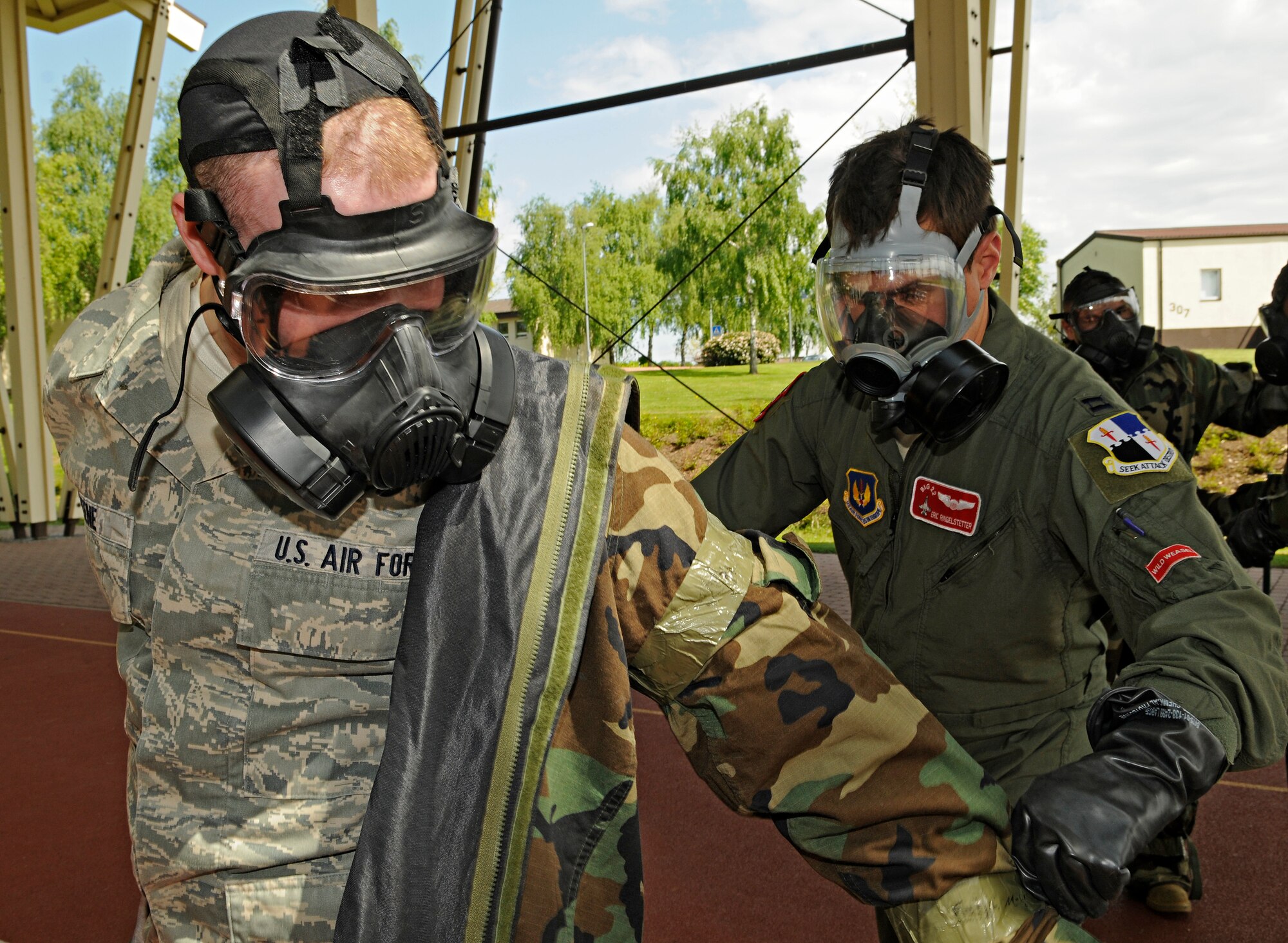 SPANGDAHLEM AIR BASE, Germany – Capt. Eric Ringelstetter, 22nd Fighter Squadron, removes a simulated, contaminated overgarment from Airman 1st Class Justin Greene, 22nd FS, at the third station of a contamination control area May 20. Members from several units volunteered to process through the CCA in preparation for the upcoming NATA Force Evaluation. (U.S. Air Force photo/Senior Airman Benjamin Wilson)