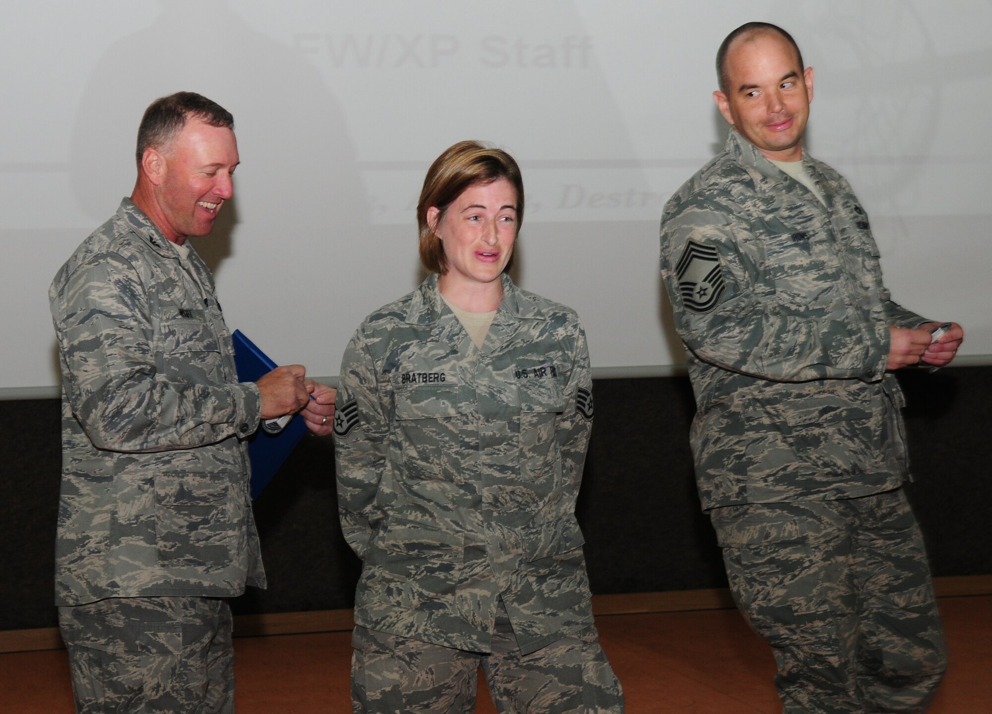 SPANGDAHLEM AIR BASE, Germany -- Col. Tip Wight, left, 52nd Fighter Wing commander, and Chief Master Sgt. Michael Irons, 52nd FW acting command chief, surprise Staff Sgt. Karla Bratburg, 52nd Communications Squadron, with a STEP promotion to technical sergeant at a commander’s call May 13 at the Skelton Memorial Fitness Center. Exceptional performers are awarded STEP promotions and assume the new rank upon announcement.  (U.S. Air Force photo/Staff Sgt. Heather M. Norris)