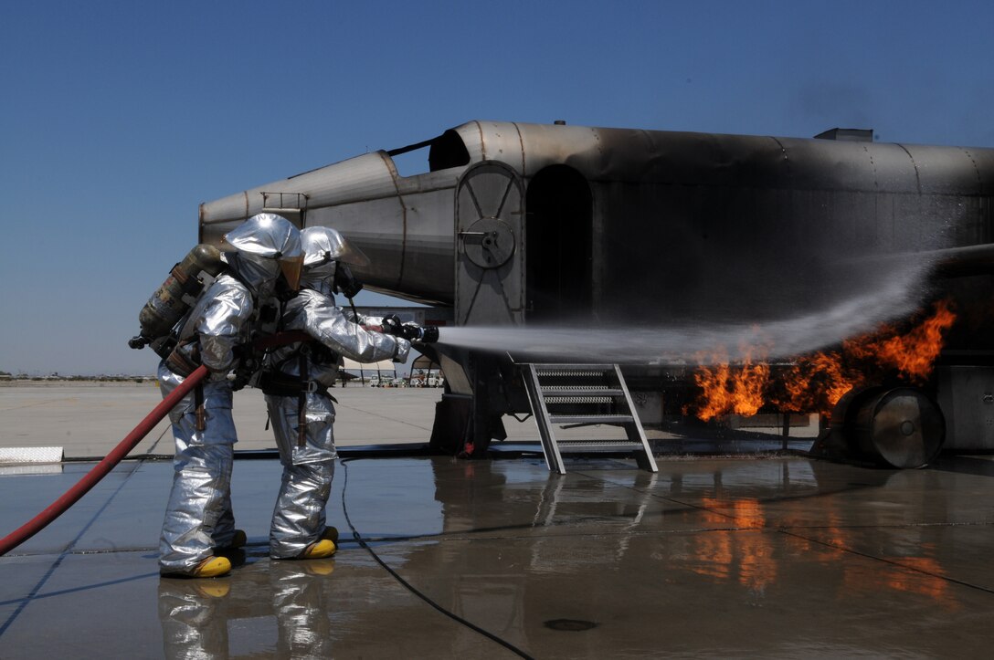 Cpl. Jordan Rowley, left, Marine Wing Support Squadron 371 firefighter, helps Laura Temple, Marine Attack Squadron 211 spouse, put out a controlled fire on a mock aircraft at the Marine Corps Air Station in Yuma, Ariz., here during VMA-211’s Jane Wayne Day May 21, 2010. More than 20 spouses spent the day touring the station and experiencing some of what Marines go through. “I’ve reached a whole new level of respect for my husband and every other Marine,” said Christina Belanger, squadron spouse.
