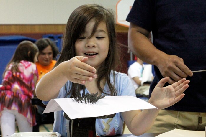 Zoe Pejsa, a 1st grade Matthew C. Perry Elementary School student, conducts a science experiment using magnets during the Super Science Saturday fair held at the M.C. Perry Elementary school gym here May 22. The fair provided interactive hands on learning for parents and students who attend the event.