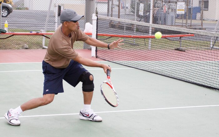 Simeon Cadavos, leading chief with 11th Dental Co., speeds toward the net to recieve the tennis ball and send it right back to the other side for a final match win with a score of 8-6 during the Spring Tennis Tournament at the::r::::n::tennis courts here May 22.