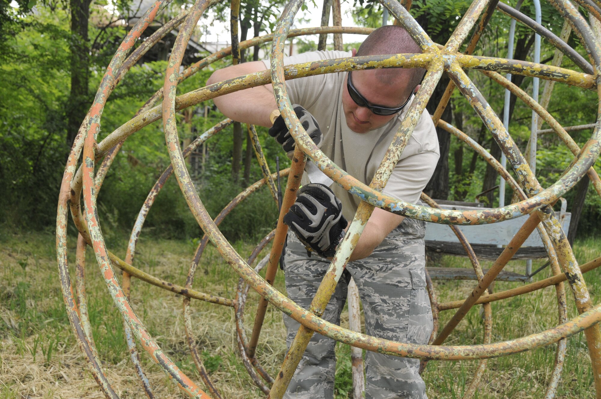 GRAF IGNATIEVO AIR FORCE BASE, Bulgaria - Staff Sgt. Brian Maas, a fire fighter with the 48th Civil Engineer Squadron at RAF Lakenheath, England, scrapes paint from playground equipment here May 21, 2010. Airmen here for Sentry Gold, a joint-training exercise designed to integrate the Bulgarian air force into NATO operations and build partnership capacities between the two air forces, donated $1,600 and volunteered almost 1,000 man hours for the renovation of a park in nearby village Graf Ignatievo. (Photo by Tech. Sgt. Chris Stagner)