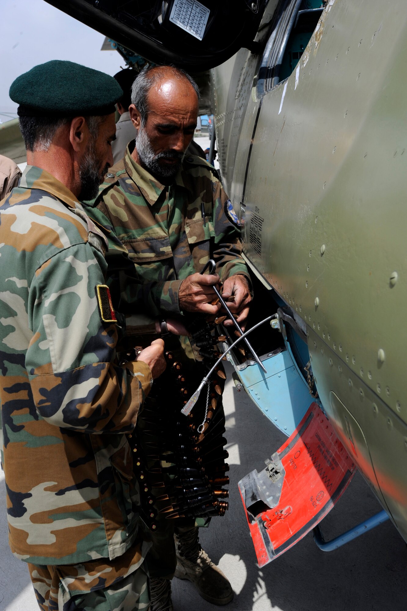 Sergeant Pacha Ghul, left, and Lt. Amin Ullah, both Aghanistan National Army Air Coprs weapons loaders, put new 12.7 mm rounds into a Yak-B Gatling gun on an MI-35 Hind E attack helicopter after a training mission May 15, 2010, at Kabul International Airport, Afghanistan. With help from Czech Republic and Hungarian Operational Mentor and Liaison Team members, Master Sgt. Raymond Rogers Jr., 440th Air Expeditonary Advisory Squadron armament and ammunition flight advisor, helped train 17 ANAAC soldiers on MI-35 and MI-17 weapons loading and unloading, armament storage, safety, weapons accountability, NATO standards, and leadership skills. (U.S. Air Force photo by Tech. Sgt. Oshawn Jefferson, released)