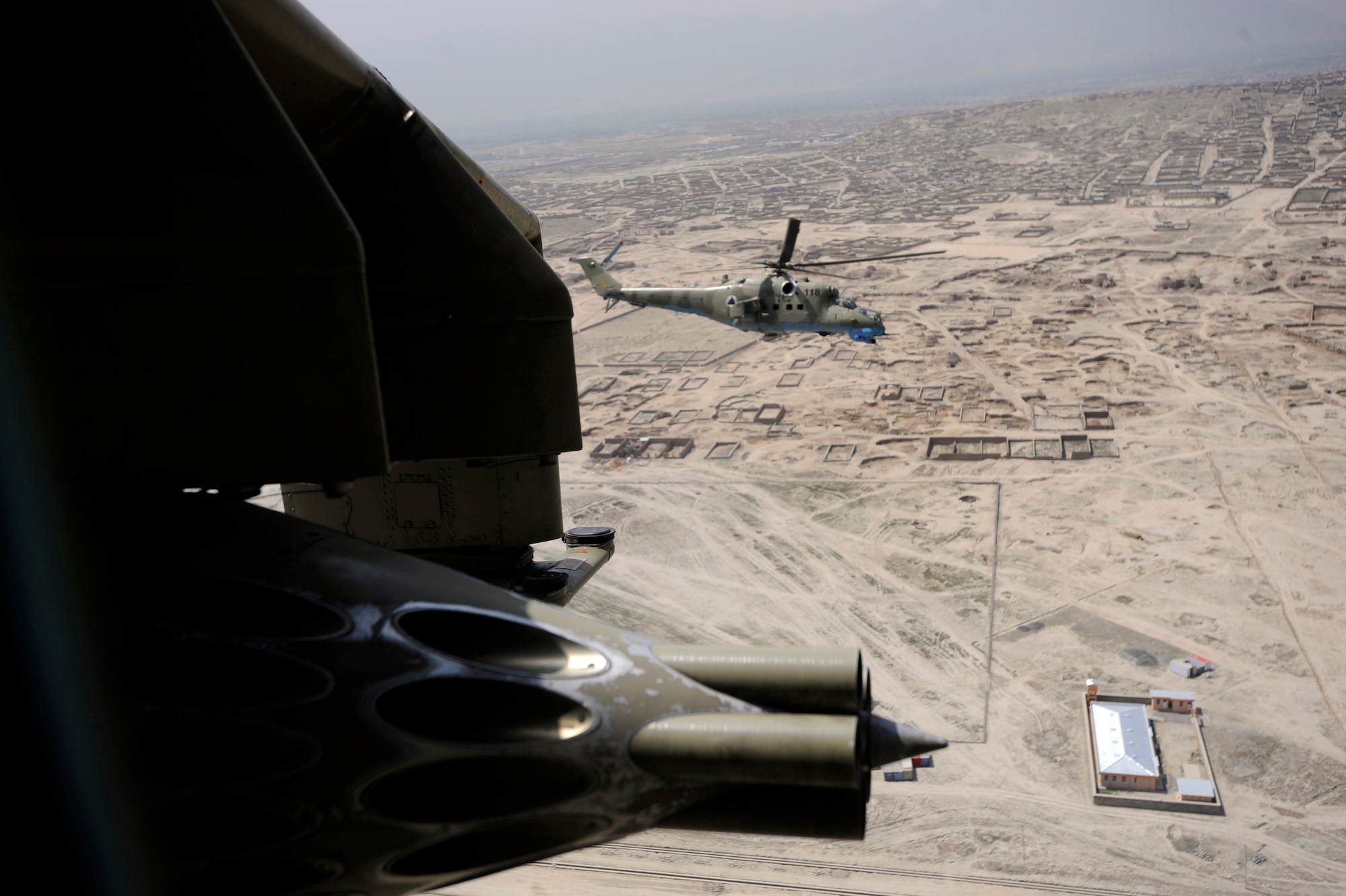 A photo taken from a window in an Afghan National Army Air Corps MI-35 Hind helicopter of another Mi-35 Hind E helicopter piloted  by Maj. Bela Lazar, Hungarian Operational Mentoring Liaison Team commander, and Capt. Gholar Mohaiudin, Afghanistan National Army Air Corp MI-35 pilot, May 15, 2010, over Afghanistan. (U.S. Air Force photo/Tech. Sgt. Oshawn Jefferson, released)
