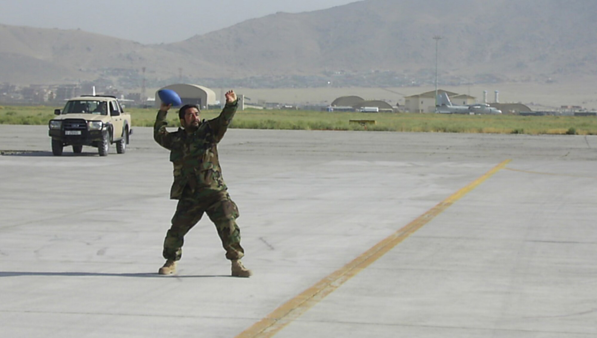 Master Sgt. Abdul Wahid, Afghanistan National Army Air Corps weapons loader, throws a football on the flightline to pass the time between Mi-35 Hind E helicopter training sorties May 15, 2010, at Kabul International Airport, Afghanistan. While teaching the Afghans the weapons loadings skills for MI-35 and MI-17 aircrews to be effective on the battle field, Sergeant Rogers also taught his ANAAC soldiers another important skill, how to throw a football.  (U.S. Air Force photo/Tech. Sgt. Oshawn Jefferson, released)
