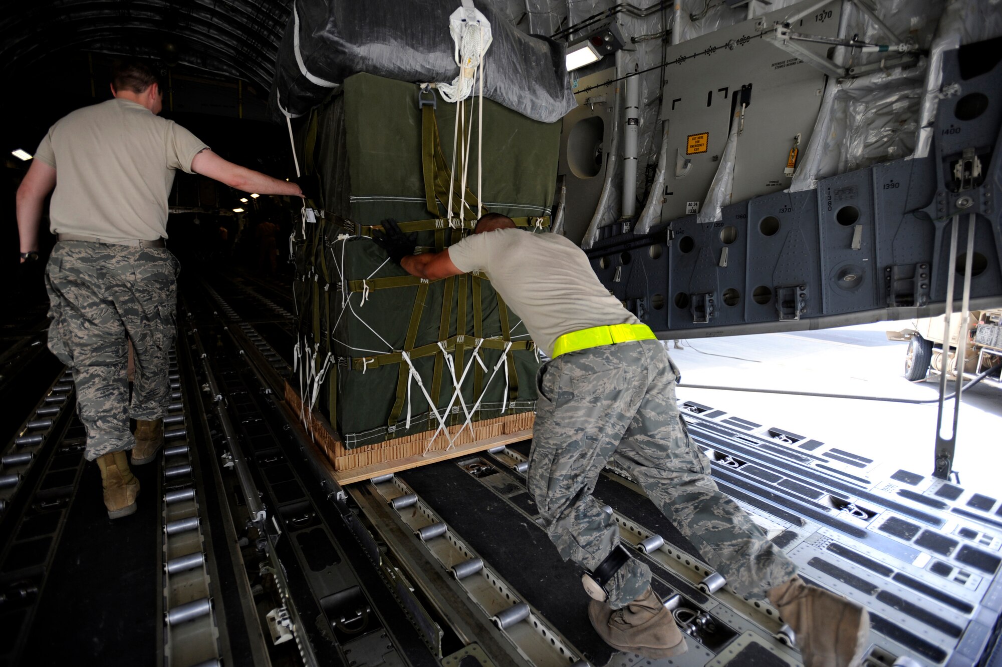 Senior Airman Brandon Nontelle, a C-17 Globemaster III loadmaster assigned to the 816th Expeditionary Airlift Squadron, and Senior Airman Jason Caro, an aerial porter assigned to the 8th Expeditionary Aircraft Maintenance Squadron, load container delivery system bundles aboard a C-17 for an airdrop mission, May 9, 2010, at a base in Southwest Asia. (U.S. Air Force photo/Staff Sgt. Manuel J. Martinez, released)