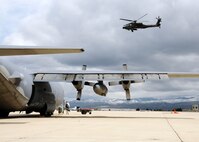 Staff Sgt. Travis Hooper, 179th Maintenance Group, refills a MC-130E Combat Talon with liquid oxygen as an AH-64 Apache helicopter from the Idaho Army National Guard lifts off May 6 at Gowen Field, Idaho.  919th Special Operations Wing maintainers, along with the 179th were sent to Boise, Idaho, to prepare four Talons to take off for one more mission – a flight into retirement and decommissioning.  Three of the Talons flew to Davis-Monthan Air Force Base, Ariz.  The other went to Hurlburt Field, Fla., to be placed in the Air Force Special Operations Command airpark.  (U.S. Air Force photo/Tech. Sgt. Samuel King Jr.)