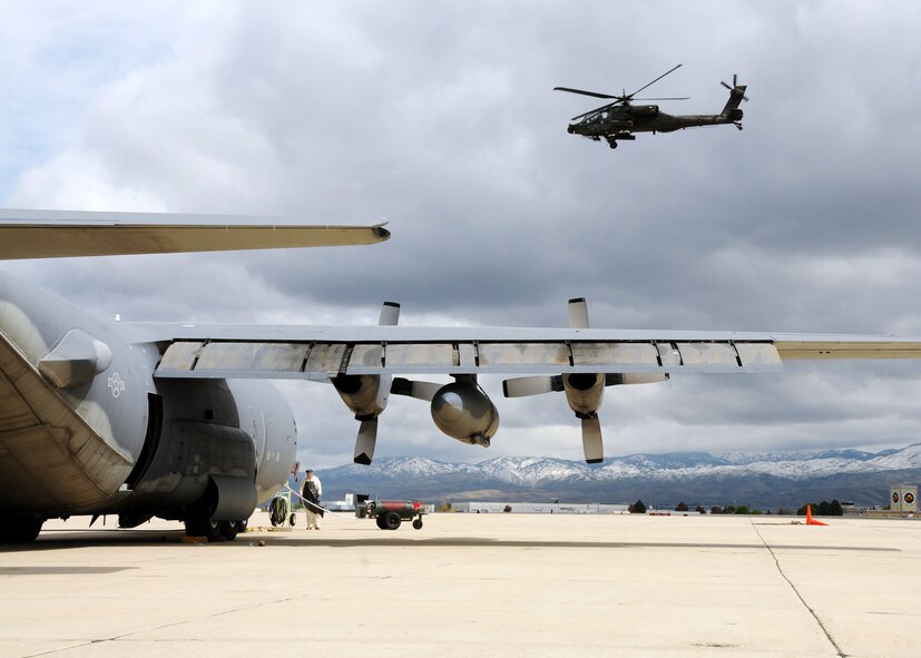 Staff Sgt. Travis Hooper, 179th Maintenance Group, refills a MC-130E Combat Talon with liquid oxygen as an AH-64 Apache helicopter from the Idaho Army National Guard lifts off May 6 at Gowen Field, Idaho.  919th Special Operations Wing maintainers, along with the 179th were sent to Boise, Idaho, to prepare four Talons to take off for one more mission – a flight into retirement and decommissioning.  Three of the Talons flew to Davis-Monthan Air Force Base, Ariz.  The other went to Hurlburt Field, Fla., to be placed in the Air Force Special Operations Command airpark.  (U.S. Air Force photo/Tech. Sgt. Samuel King Jr.)