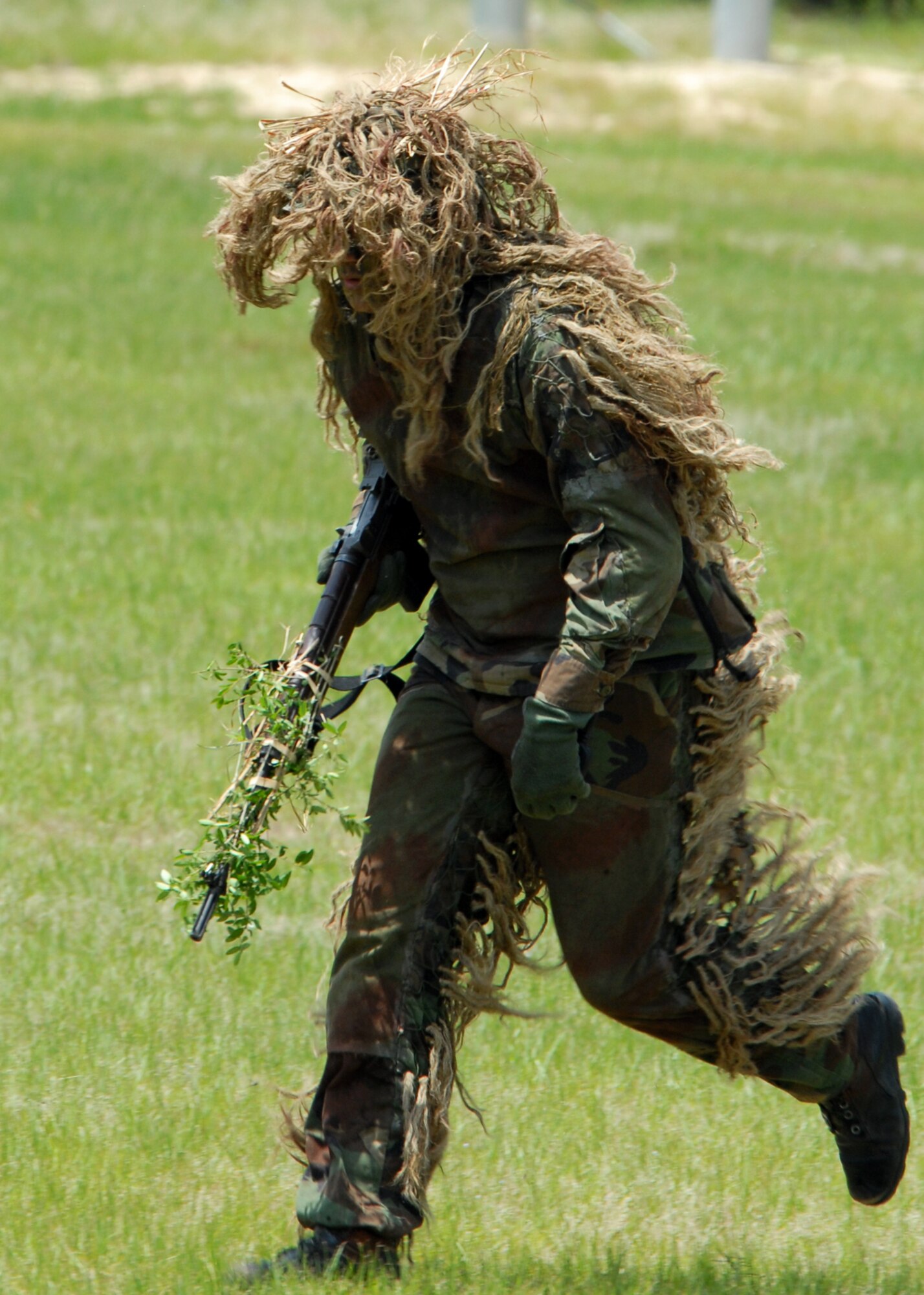 A camouflaged sniper moves toward the group of rangers during the Ranger Open House May 22.  The event was a chance for the public to learn how Rangers train and operate in extreme situations. The event displays such as dive equipment, weapons, and zodiac boats and demonstrations like hand-to-hand combat, parachute jump, and an urban operations demonstration.  (U.S. Air Force photo/Samuel King Jr.)
