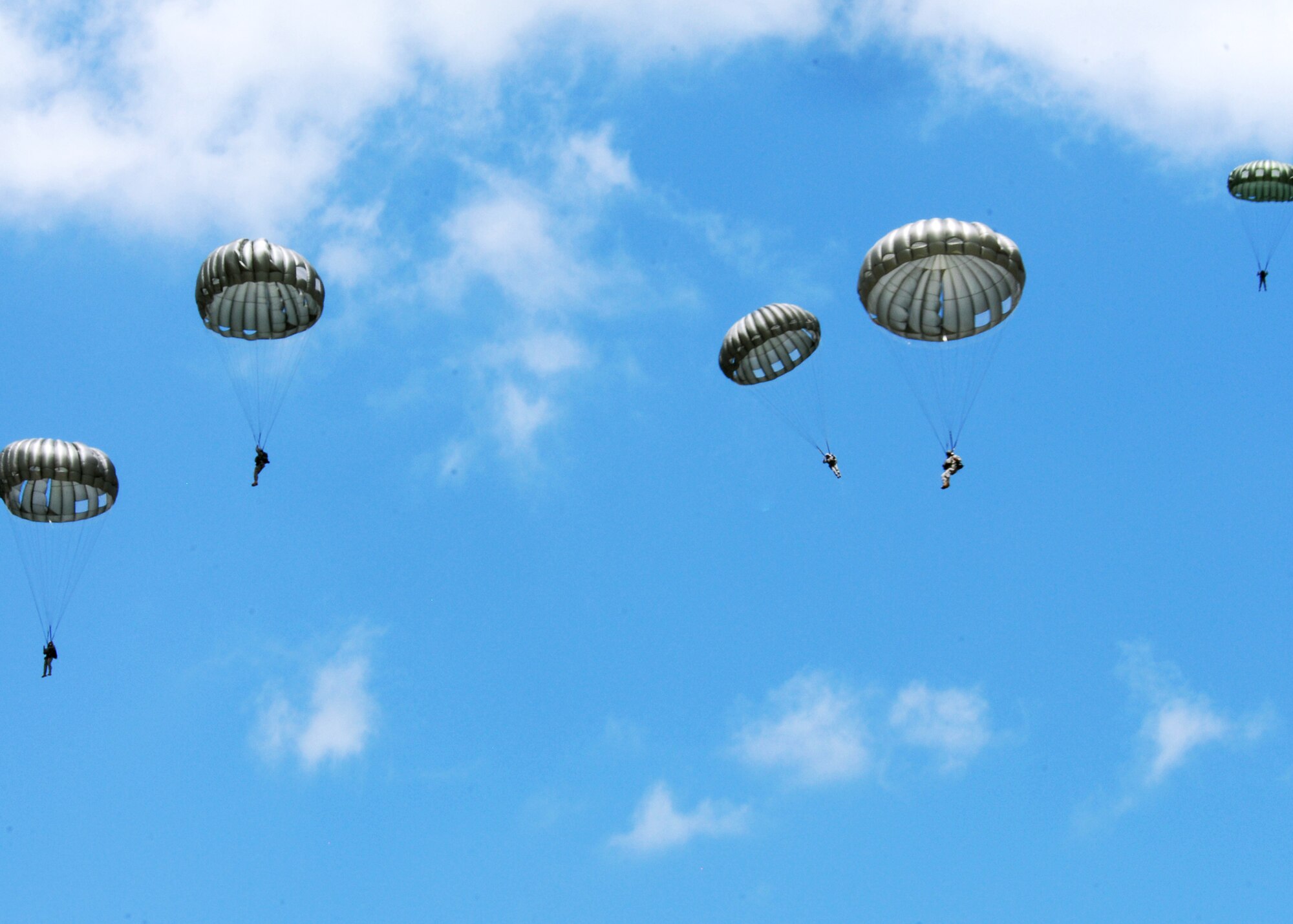 Rangers drift down after jumping out of a helicopter as part of a parachute jump demonstration during the Ranger Open House May 22.  The event was a chance for the public to learn how Rangers train and operate in extreme situations. The event displays such as dive equipment, weapons, and zodiac boats and demonstrations like hand-to-hand combat, parachute jump, and an urban operations demonstration.  (U.S. Air Force photo/Samuel King Jr.)