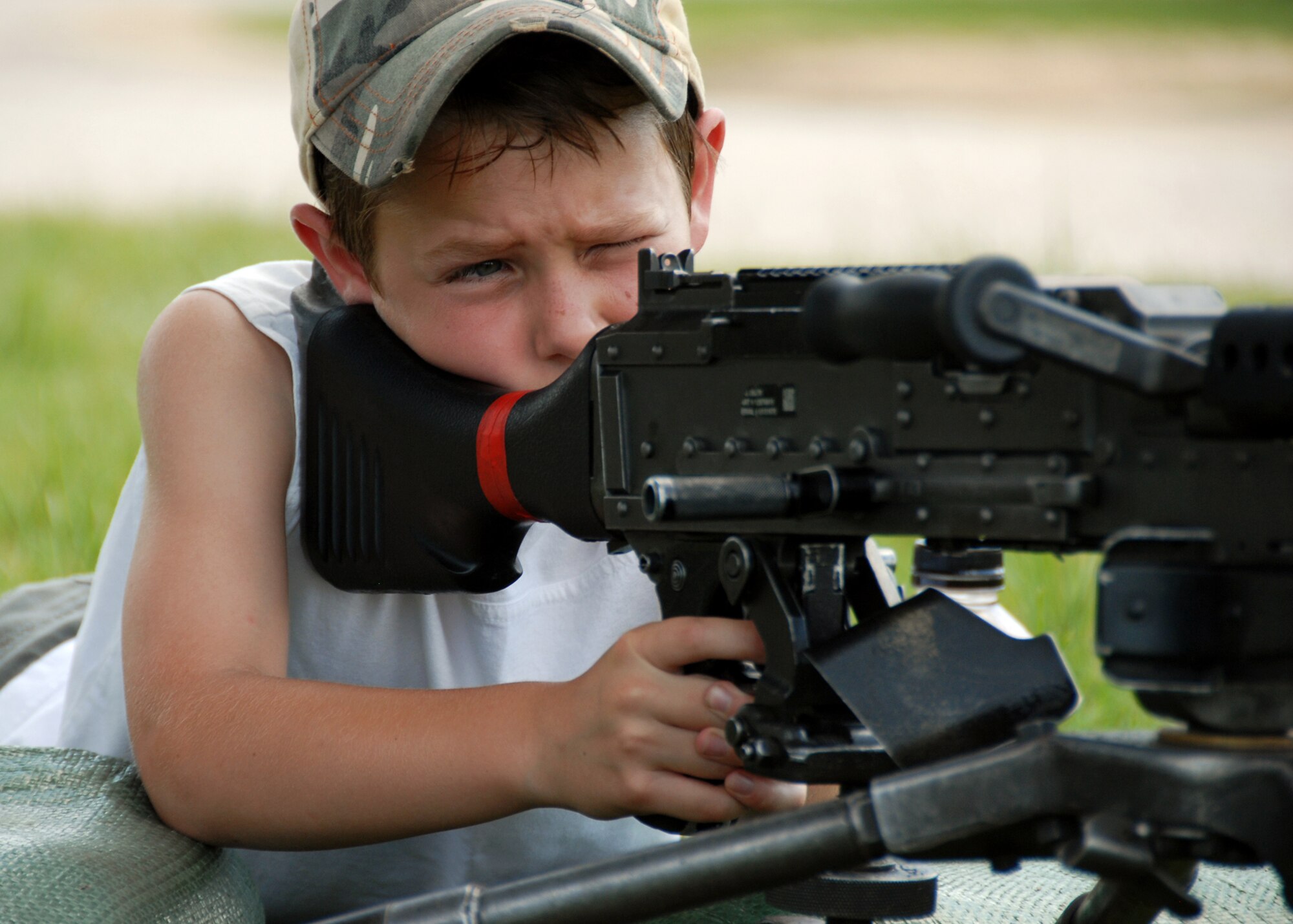 A “trainee” tests out the machine guns on display during the 6th Ranger Training Battalion Open House May 22.  The event was a chance for the public to learn how Rangers train and operate in extreme situations. The event displays such as dive equipment, weapons, and zodiac boats and demonstrations like hand-to-hand combat, parachute jump, and an urban operations demonstration.  (U.S. Air Force photo/Samuel King Jr.)