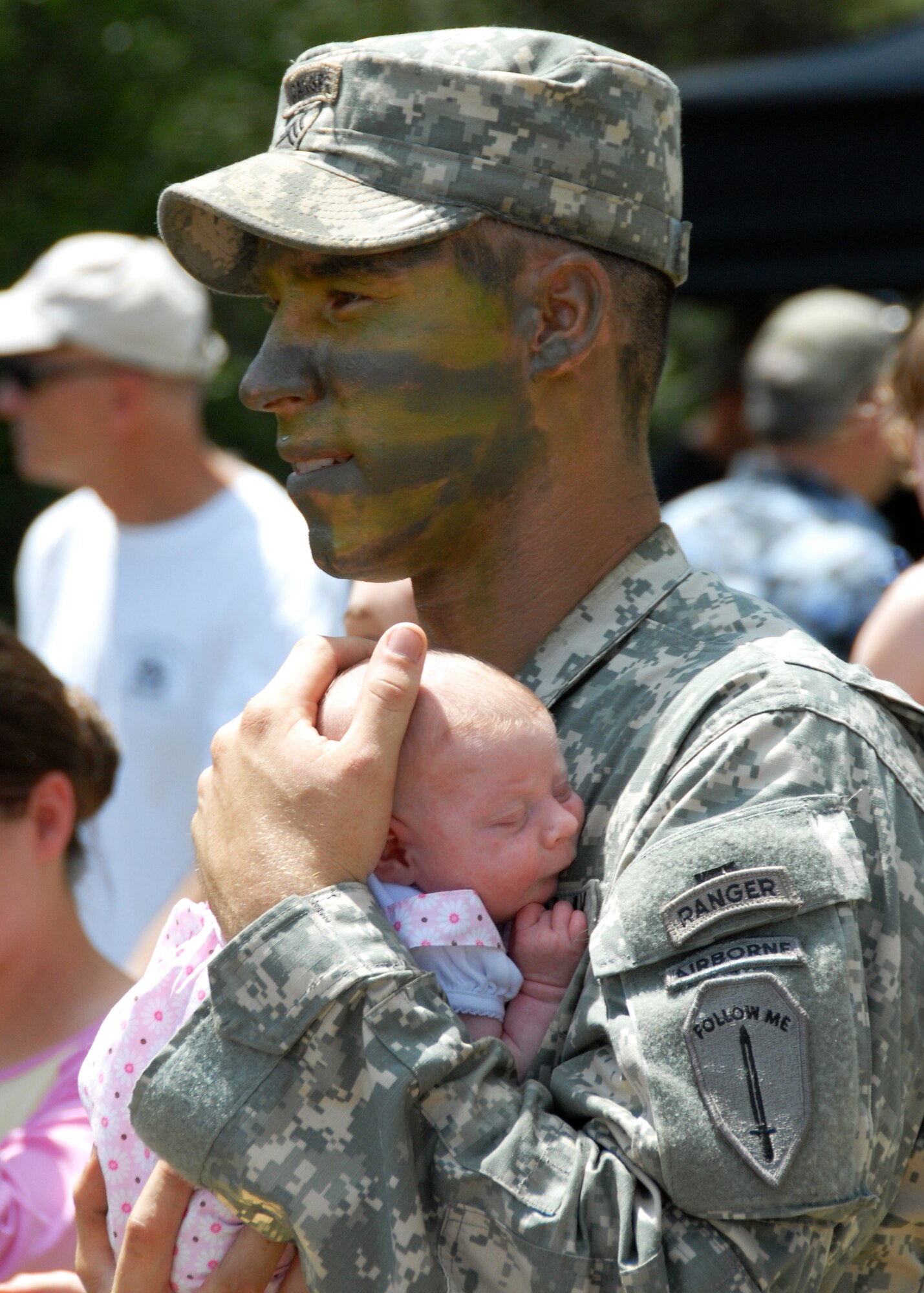 An Army Ranger carries his new-born daughter at the 6th Ranger Training Battalion Open House May 22.  The event was a chance for the public to learn how Rangers train and operate in extreme situations. The event displays such as dive equipment, weapons, and zodiac boats and demonstrations like hand-to-hand combat, parachute jump, and an urban operations demonstration.  (U.S. Air Force photo/Samuel King Jr.)