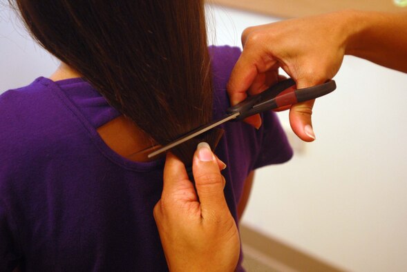 JOINT BASE PEARL HARBOR HICKAM, Hawaii – Tech. Sgt. Jenet Akerson, 692nd Intelligence, Surveillance and Reconnaissance Group Detachment 1, cuts a lock of hair from Leilani Hanus, 5, during the Give a Little, Give a Lock event here, May 21. All hair and money gathered through this donation is sent to Locks of Love. Locks of Love, a public non-profit organization, provides hairpieces to financially disadvantaged children in the United States and Canada under age 21 suffering from long-term medical hair loss. (U.S. Air Force photo/Senior Airman Gustavo Gonzalez)