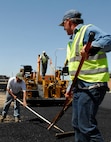 MINOT AIR FORCE BASE, N.D. – Contractors Mark Hoffman(right) and Brad Lee(left) use a rake to level fresh asphalt in the J.R. Rockers parking lot here May 20.   The contractors are working with the 5th Civil Engineer Squadron on an overhaul project of the parking lot.  This is just one of many construction projects on base this summer.  (U.S. Air Force photo by Staff Sgt. Miguel Lara III)