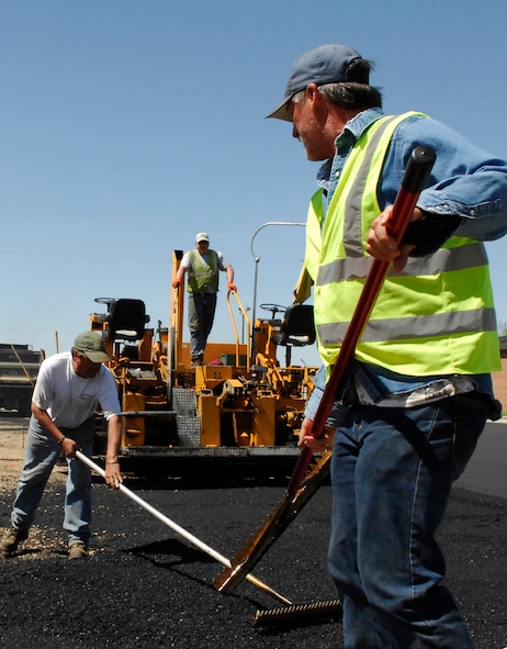 MINOT AIR FORCE BASE, N.D. – Contractors Mark Hoffman(right) and Brad Lee(left) use a rake to level fresh asphalt in the J.R. Rockers parking lot here May 20.   The contractors are working with the 5th Civil Engineer Squadron on an overhaul project of the parking lot.  This is just one of many construction projects on base this summer.  (U.S. Air Force photo by Staff Sgt. Miguel Lara III)