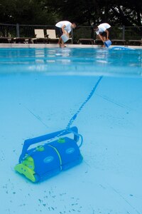 Angel Saavedra and Joshua Caslill, Randolph Air Force Base lifeguards, work together to clean around the pool deck while the skimmer cleans the pool during preparation for the 2010 swimming season. (U.S. Air Force photo/Steve Thurow)