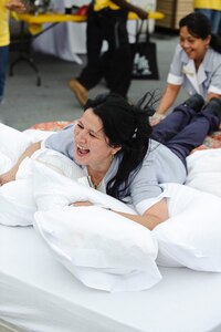 Amanda Mancha, with the 902nd Force Support Squadron, is pushed toward the finish line during a team building exercise, in which participants made a bed to Air Force standards and raced across the finish line during a safety day event to kick off the 101 Critical Days of Summer. (U.S. Air Force photo/Steve Thurow)