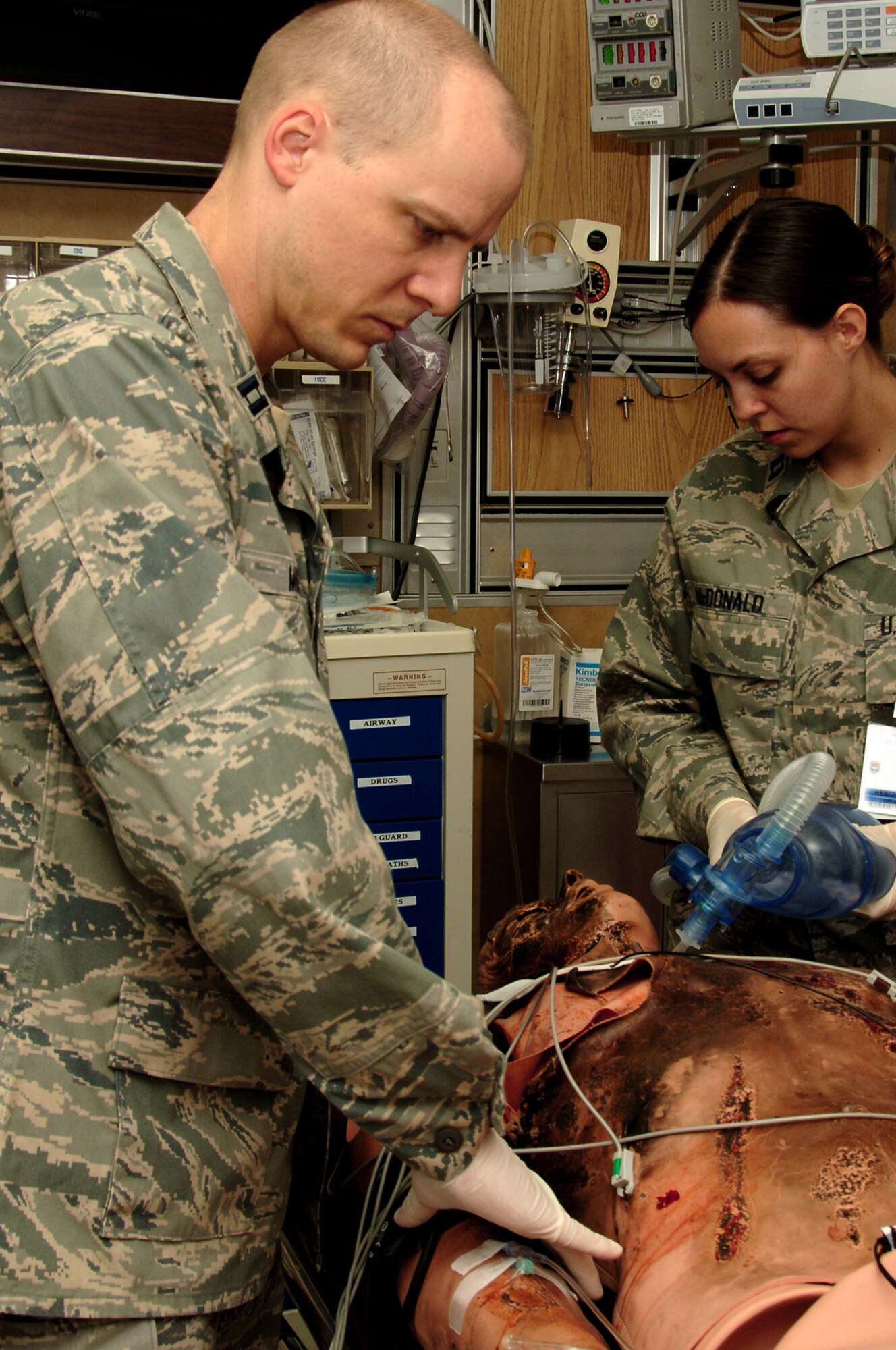 Capt. (Dr.) Tylan Muncy and Capt. (Dr.) Carolyn McDonald evaluate a burn patient during simulation grand rounds May 21, 2010, in the Wilford Hall Medical Center simulation center at Lackland Air Force Base, Texas. The simulation cases can be adapted and created to focus on the needs of a wide range of learners to include paramedics, nurses, medical students and physicians. Doctor Muncy is with the 59th Surgical Specialties Squadron. Doctor McDonald is with the 59th Emergency Medicine Squadron. Both doctors are emergency medicine residents. (U.S. Air Force photo/Senior Airman Nicole Mickle)
