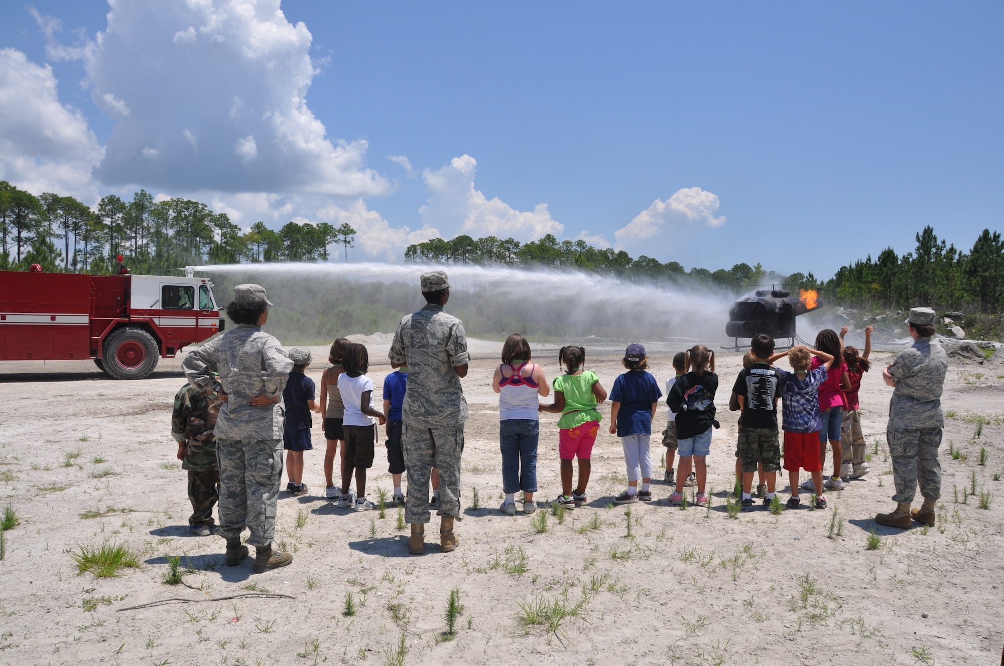 A fire truck extinguishes a simulated helicopter fire May 22 during the Jr. Raptor program. (U.S. Air Force photo by Airman 1st Class Rachelle Elsea)