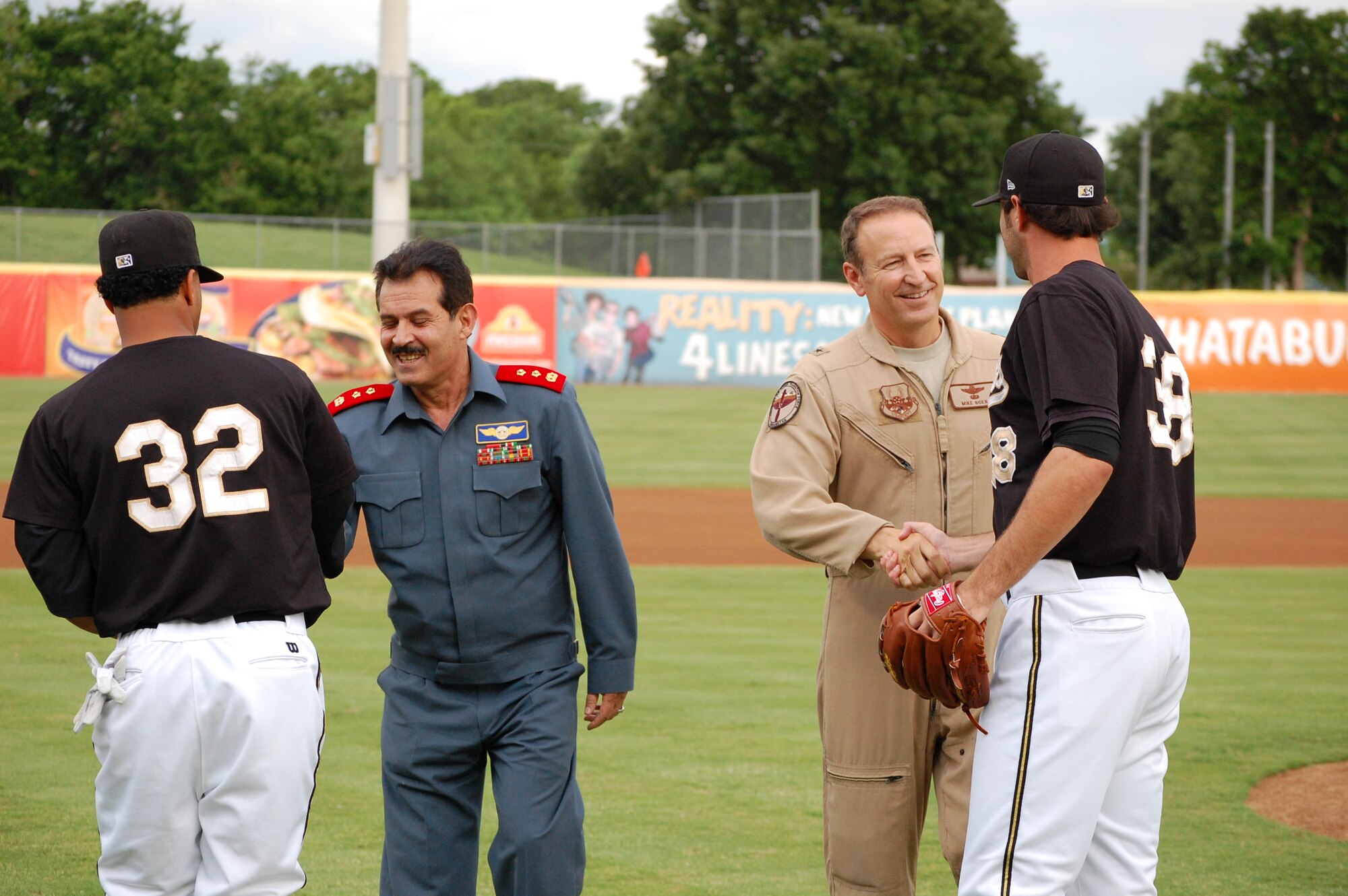Maj. Gen. Mohammad Dawran, Afghan National army air corps, center, and Brig. Gen. Michael Boera, Coalition Air Power Transition Force commanding general, center,  shake hands with Missions 2nd Baseman, Jorge Minyeti, far left, and pitcher Craig Italino, after they threw out the dual-first pitch of the game at Wolf Stadium May 23 in San Antonio, Texas. General Dawran is visiting Air Education and Training Command to receive updated information on current and future security assistance and cooperation training for the ANAAC. General Boera is working to stand up a robust ANAAC center of excellence and he is exploring more in-depth maintenance training between the two nations. Since the establishment of the Kabul Air Corps Training Center in 2007, in Afghanistan, more than 1,100 Afghani military members have received training in air corps orientation, air traffic control, fire fighting, aircraft maintenance, loadmaster duties and gunner training. (U.S. Air Force photo/Master Sgt. Paul Kilgallon)