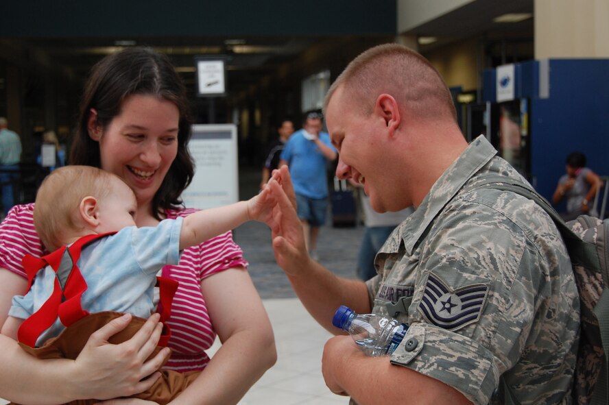 WRIGHT-PATTERSON AIR FORCE BASE, Ohio – Tech. Sgt. Joseph Heitzenrater, 445th Civil Engineer Squadron, receives a high-five from his son, Vincent, as his wife, Julia, looks on.  Sergeant Heitzenrater was greeted by family and friends at the Dayton International Airport May 20 after returning from a 120-day deployment to Kirkuk Regional Air Base, Iraq, where he was assigned as a fire protection crew chief with the 506th Expeditionary Civil Engineer Squadron. (U.S. Air Force photo/Maj. Cynthia Harris)