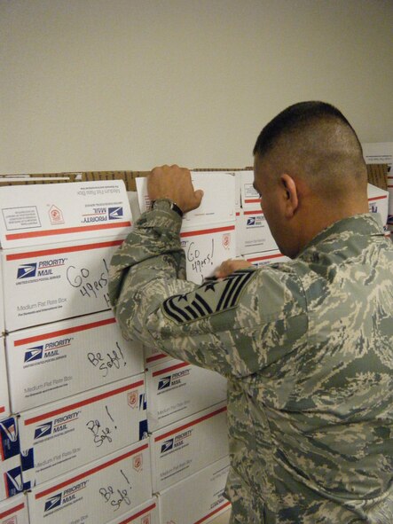 HOLLOMAN AIR FORCE BASE, N.M. -- Chief Master Sgt. Gerardo Tapia, 49th Fighter Wing command chief, writes on care packages, May 11, 2010, before they are shipped to deployed troops in a project called Operation Care Package. More than 50 volunteers came out to pack 385 care packages for Team Holloman men and women who are currently deployed. Each box contained items such as cookies, beef jerky, hand sanitizer, foot powder, puzzle books, hand-written cards from students at Holloman schools and thank-you letters from New Mexico Congressmen. (Courtesy photo / Released)