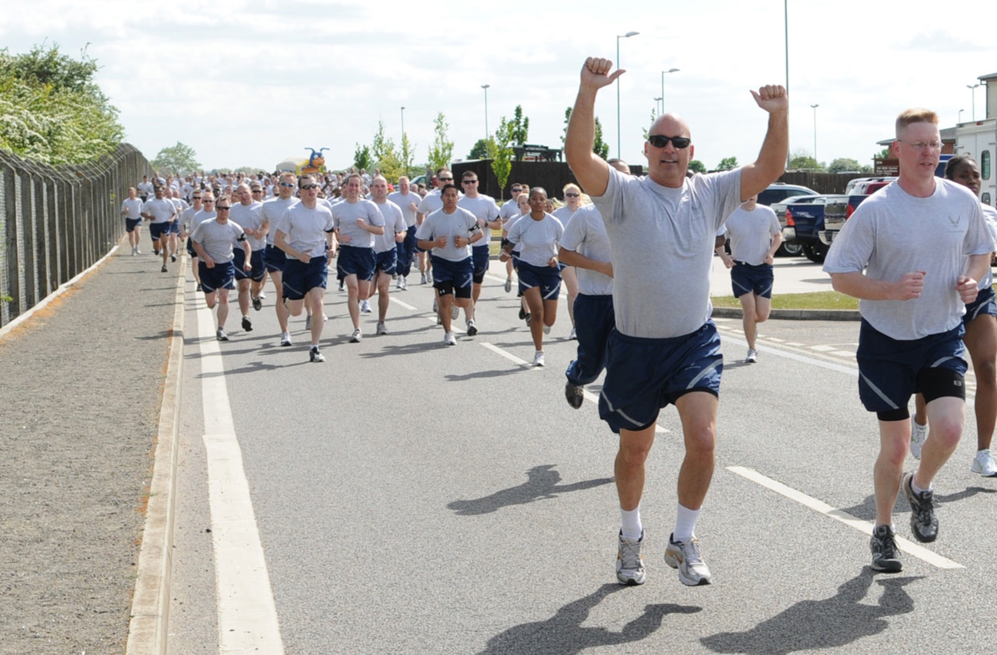 Chaplain (Lt. Col.) Frederick Viccellio (arms raised), 100th Air Refueling Wing chaplain, and Lt. Col Davis Maulding, 100th Comptroller Squadron commander, run with their squadron members during the Team Mildenhall 5K fun run May 21. Hundreds of Airmen took part in the 5K event, which is held monthly to promote health and fitness. (U.S. Air Force photo/Karen Abeyasekere)