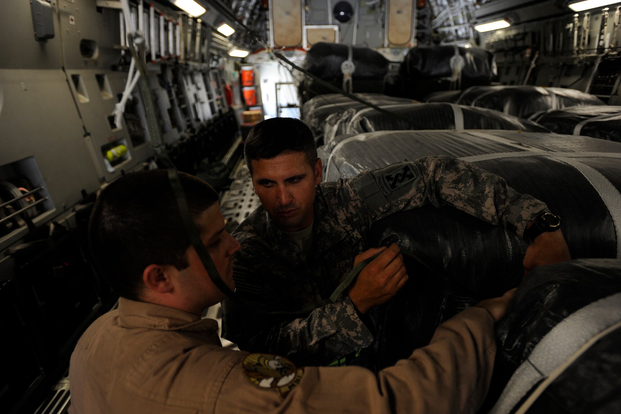 Army Sergeant 1st Class Jonathan Hall, right, an airdrop inspector assigned to the 824th Quartermaster Company, Det. 8, speaks with Staff Sgt. Bryan Carey, a C-17 Globemaster III loadmaster assigned to the 816th Expeditionary Airlift Squadron, regarding his findings during a joint inspection of container-delivery-system bundles May 9, 2010, at a base in Southwest Asia. (U.S. Air Force photo/Staff Sgt. Manuel J. Martinez/released)
