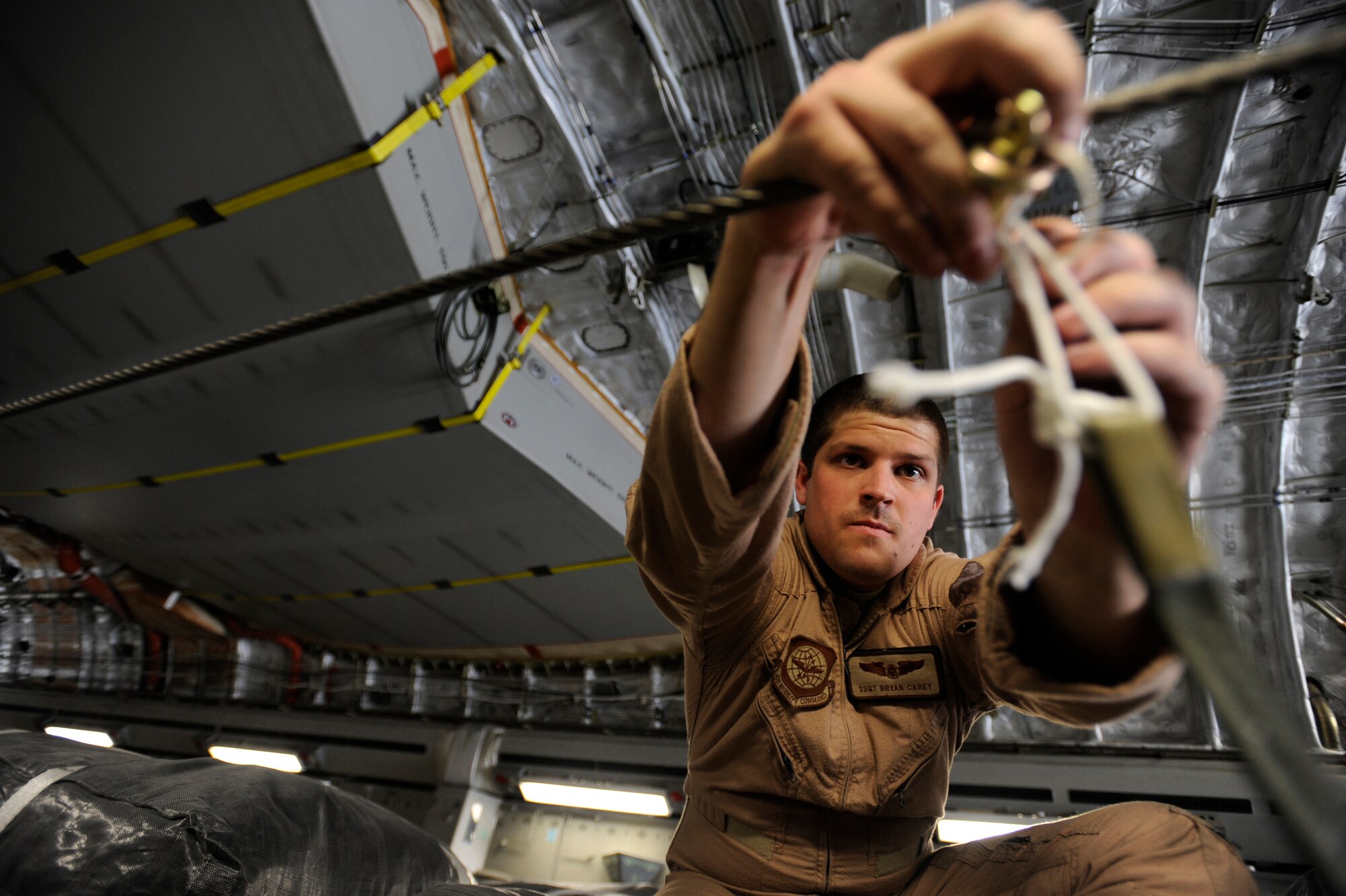 Staff Sgt. Bryan Carey, a C-17 Globemaster III loadmaster assigned to the 816th Expeditionary Airlift Squadron, hooks parachute draw cords to container-delivery-system bundles prior to take off for an airdrop mission May 9, 2010, at a base in Southwest Asia. (U.S. Air Force photo/Staff Sgt. Manuel J. Martinez/released)
