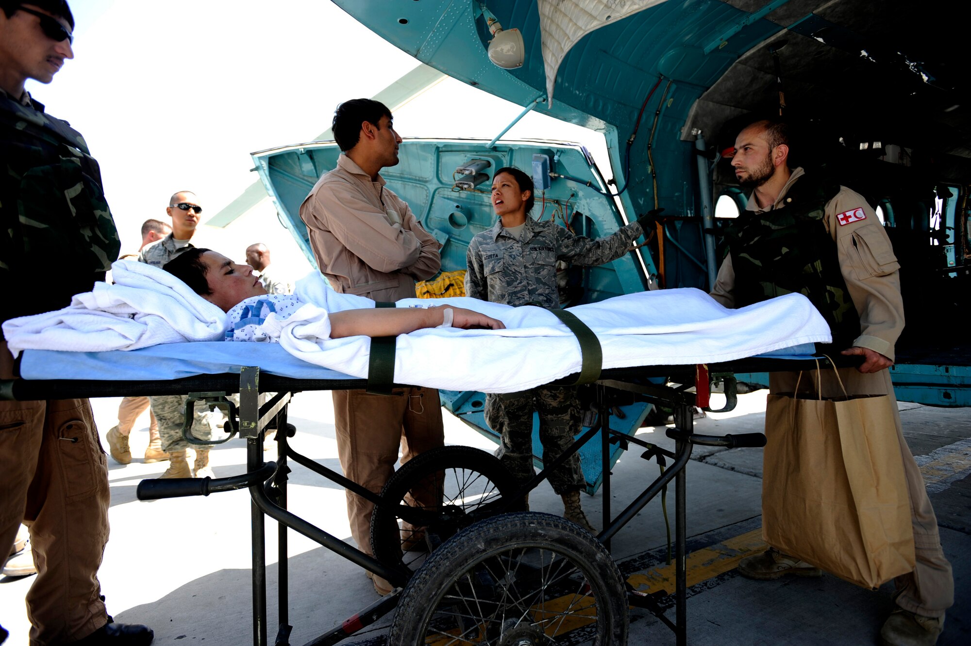 U.S. Air Force Senior Airman Daniielle Acosta, a medic assigned to the 455th Medical Operations Squadron, briefs an Afghan interpreter on patient information to pass on to Afghan National Army Air Corps flight medics, while Sgt.Abdul Salaaman, left, and Sgt.Malik Hamet, right, both ANAAC flight medics, load an Afghan boy on an Mi-17 helicopter May 12, 2010, at Bagram Airfield, Afghanistan. (U.S. Air Force photo/Staff Sgt. Manuel J. Martinez/released) 