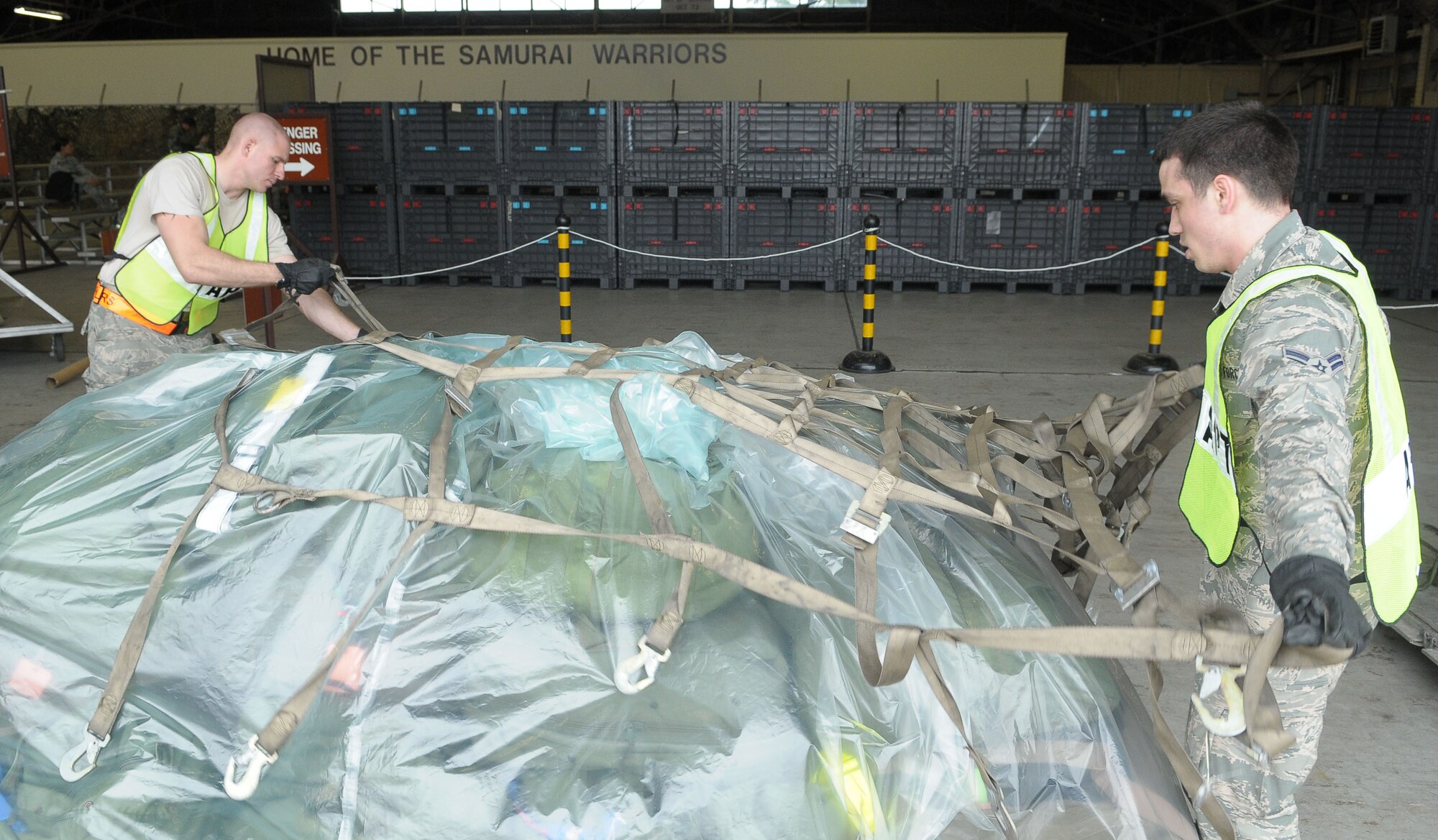 YOKOTA AIR BASE, Japan -- Airman 1st Class James Stay, (left) air passenger terminal augmentee, and Airman 1st Class Benjamin Benoit, 374th Medical Operations Squadron medical administrator, secure cargo May 24 during an operational readiness exercise. Yokota is conducting an exercise through May 27 to maintain operational readiness. (U.S. Air Force photo/Airman 1st Class Sean Martin)