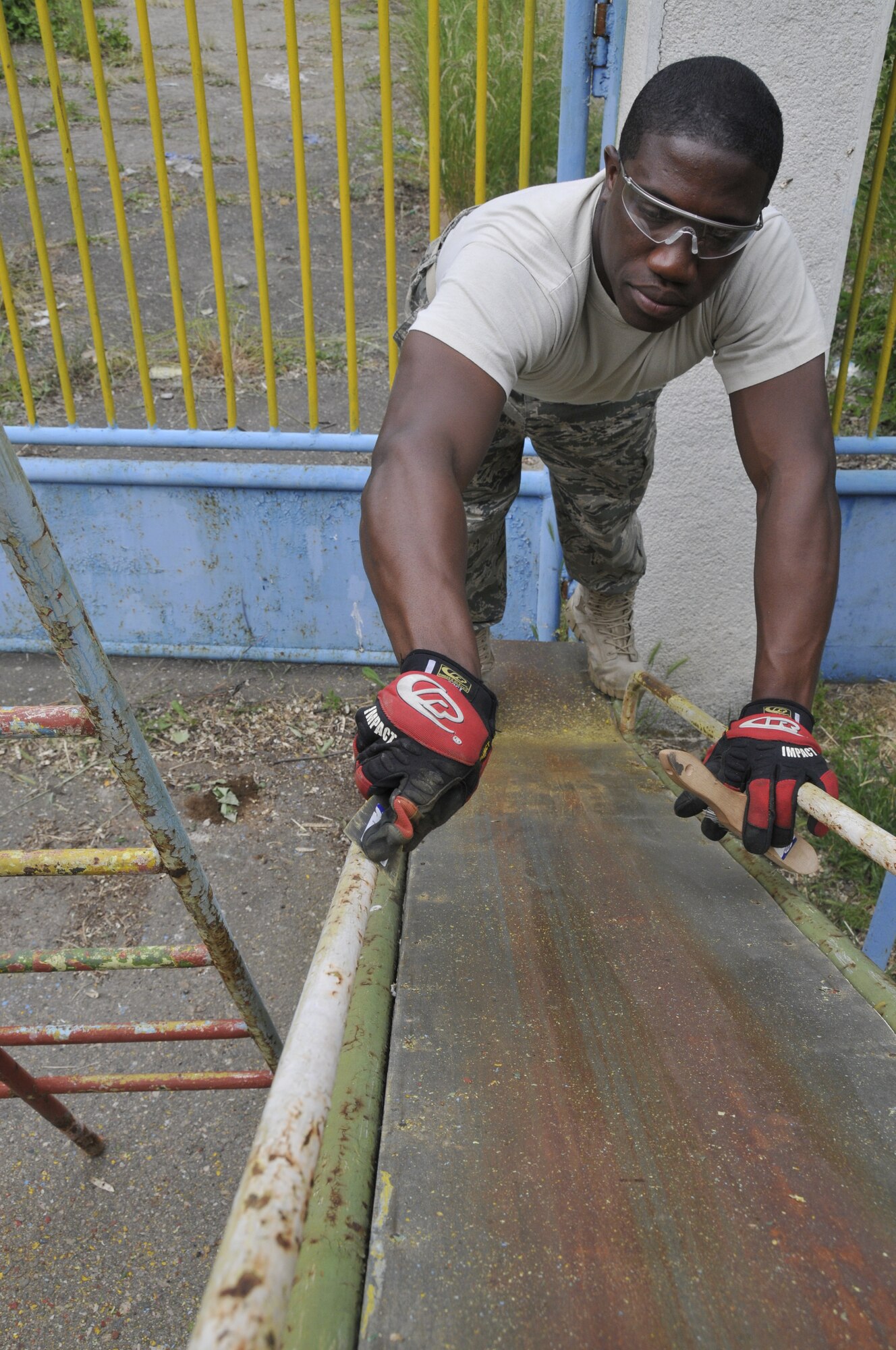 GRAF IGNATIEVO AIR FORCE BASE, Bulgaria - Senior Airman Daniel Nembhard, a fire fighter with the 48th Civil Engineer Squadron at RAF Lakenheath, England, scrapes paint from a slide here May 21, 2010. Airmen here for Sentry Gold, a joint-training exercise designed to integrate the Bulgarian air force into NATO operations and build partnership capacities between the two air forces, donated $1,600 and volunteered almost 1,000 man hours for the renovation of a park in nearby village Graf Ignatievo. (Photo by Tech. Sgt. Chris Stagner)