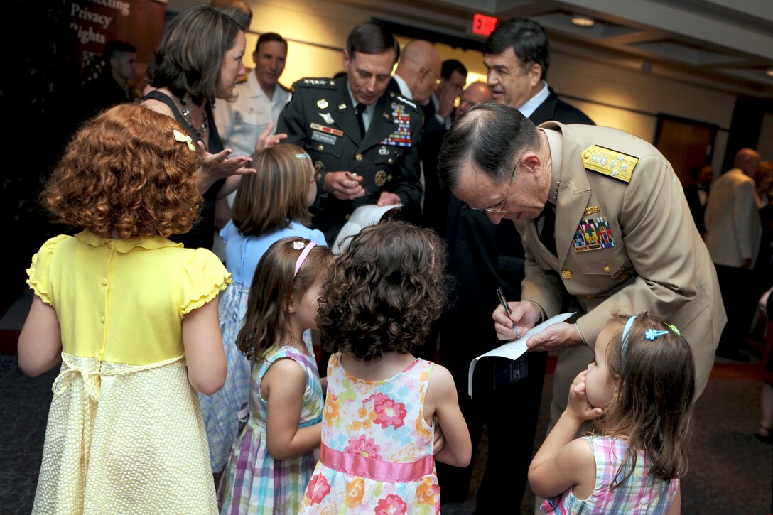 Navy Adm. Mike Mullen, chairman of the Joint Chiefs of Staff, and Army Gen. David H. Petraeus, commander of U.S. Central Command, sign autographs for the grandchildren of Army Gen. Keith Alexander during the activation ceremony of U.S. Cyber Command on Fort Meade, Md., May 21, 2010.
