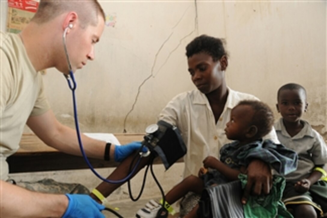 U.S. Army Sgt. Tommy Fenton (left), a medic with 94th Combat Support Hospital, out of Seagoville, Texas, listens to the heart rate of a Haitian woman during a U.S. Army Medical Readiness Training Exercise in Couteaux, Haiti, on Apr. 30, 2010.  During Operation Unified Response, U.S. and Haitian medical care providers offer free level-one medical care to Haitians in the community.  