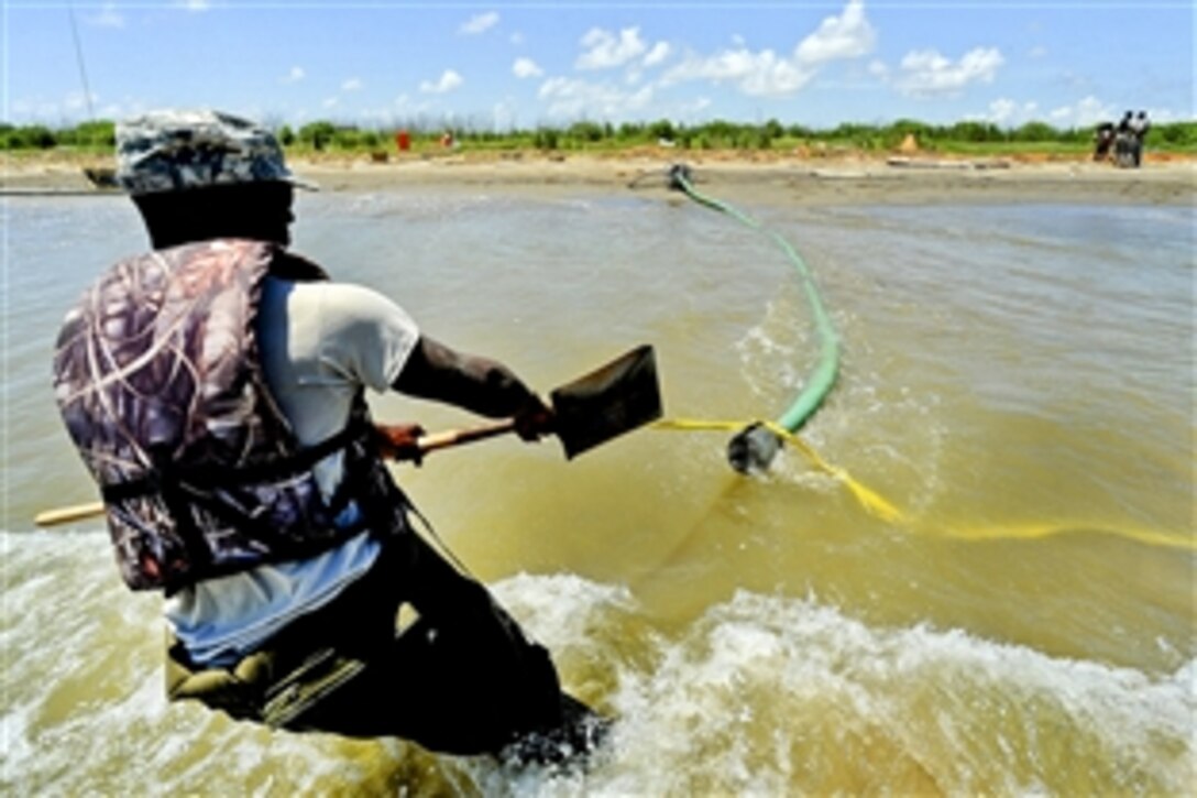 U.S. Army Pvt. Richard Jones moves the intake pipe for a water pump that is used to inflate the Tiger Dam water diversion system near the southwest pass of the Mississippi River Delta,  May 20, 2010. Jones is assigned to the Louisiana National Guard's 528th Engineer Battalion. His team is constructing a 7.1-mile-long barrier to prevent oil from coming into the wetlands.