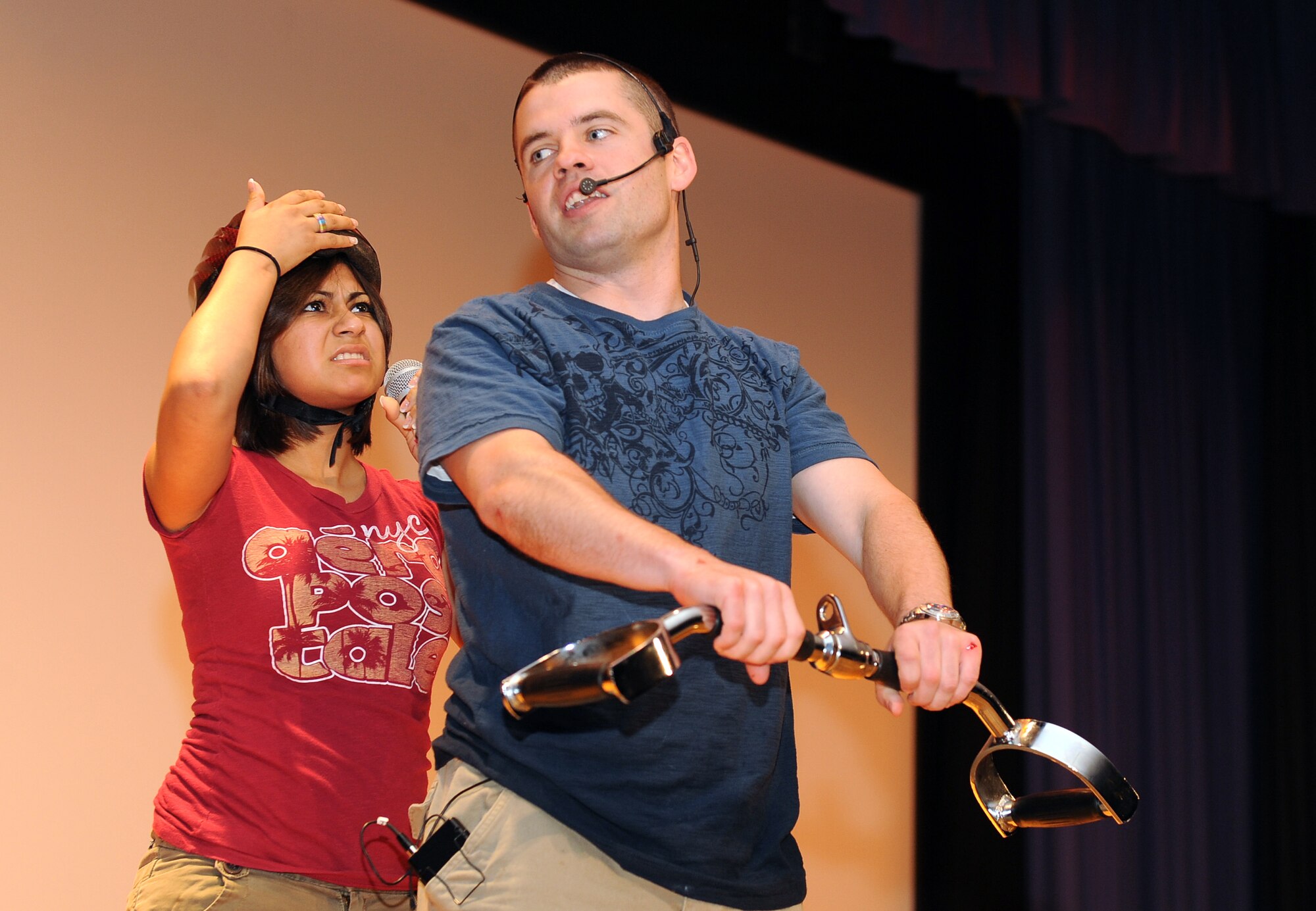LANGLEY AIR FORCE BASE, Va. -- Airman 1st Class Terry Carroll, 633d Communications Squadron wing information assurance manager, and Airman 1st Class Stephanie Reyes, 1st Medical Group pharmacy technician, simulate riding a motorcycle without a helmet during a wing safety presentation at the base theater May 14. The presentation was part of the Air Combat Command Road Show, a command-wide tour designed to stress the importance of safety and the wingman concept while entertaining Airmen. (U.S. Air Force photo/Airman 1st Class Gul Crockett)