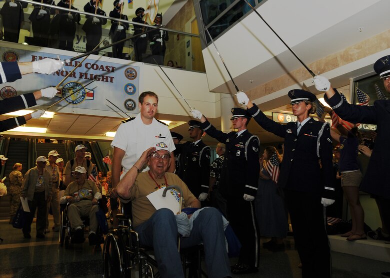 A World War II veteran salutes as he is escorted by a U.S. Navy officer through a saber cordon at the Northwest Florida Regional Airport in Eglin AFB, Fla., May 5, 2010. Several hundred citizens welcomed the veterans back to Florida from their trip to Washington D.C. (DoD photo by U.S. Air Force Senior Airman Matthew Loken)