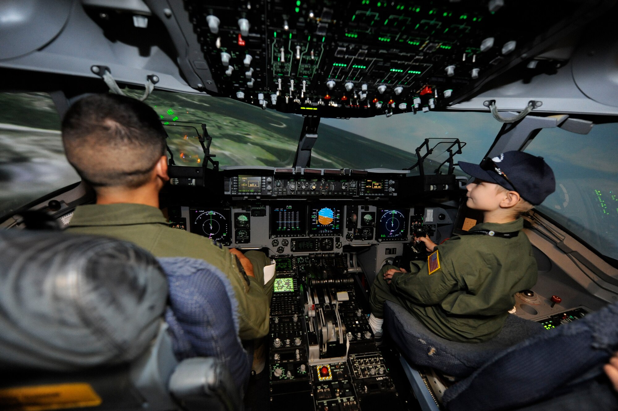 U.S. Air Force Capt. Kyle Clinton and A.J. Risor fly a C-17 simulator on Joint Base Charleston, S.C., May 21, 2010. Captain Clinton is an instructor pilot with the 15th Airlift Squadron and A.J. is the "Pilot for a Day." The Pilot for a Day program is an Air Force-wide program which helps seriously ill children to become honorary pilots for a day. The base works in conjunction with the South Carolina Make-a-Wish Foundation and the Medical University of South Carolina to identify the children who participate in the program. (U.S. Air Force photo/James M. Bowman)
