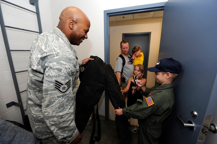 U.S. Air Force Staff Sgt. Ramon Alexander shows A.J. Risor a protective bite suite while family members look on at the 628th Security Force Squadron K-9 unit on Joint Base Charleston, S.C., May 21, 2010. Sergeant Alexander is the trainer for the K-9 unit and is with the 628th Security Forces Squadron and A.J. is the "Pilot for a Day." The Pilot for a Day program helps children and their families in the local community who have catastrophic illnesses. For many children with catastrophic, but not "terminal" illnesses, the Pilot for a Day Program is part of the recovery process. (U.S. Air Force photo/James M. Bowman)